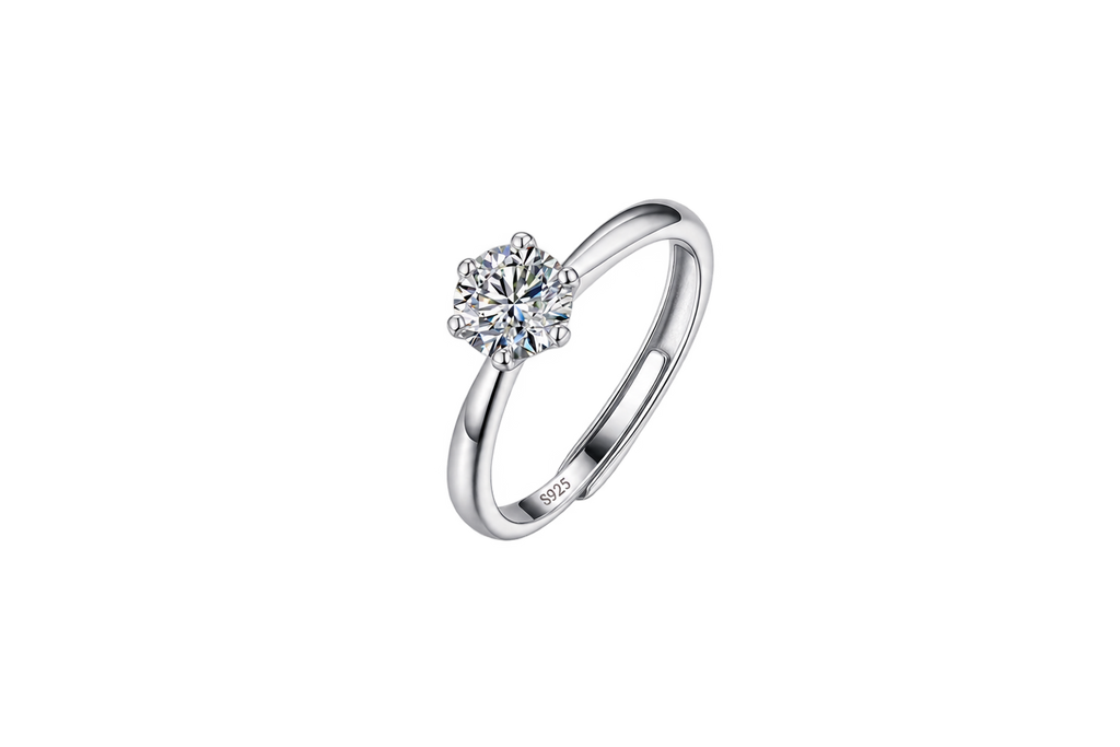 A silver solitaire engagement ring with a round brilliant-cut diamond set in a four-prong setting, shown on a plain white background. The inside of the band features a '925' sterling silver hallmark.