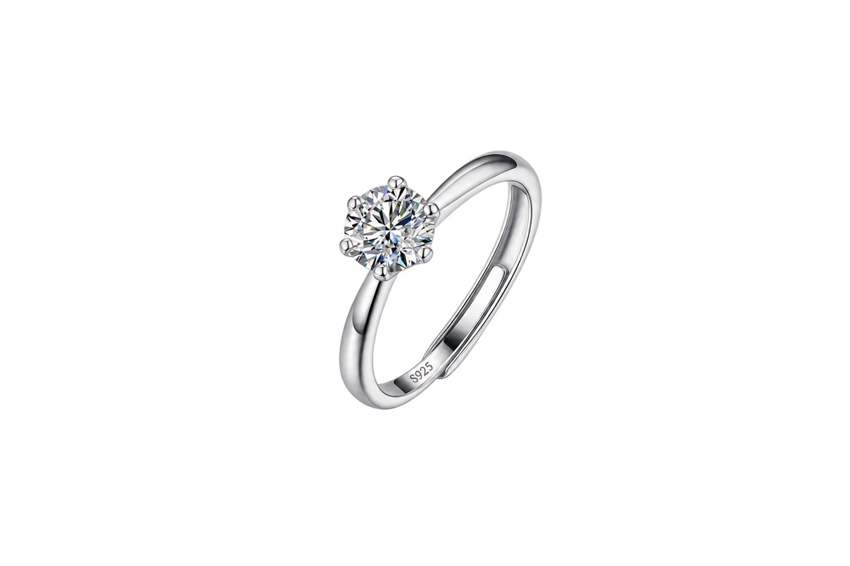 A silver solitaire engagement ring with a round brilliant-cut diamond set in a four-prong setting, shown on a plain white background. The inside of the band features a '925' sterling silver hallmark.