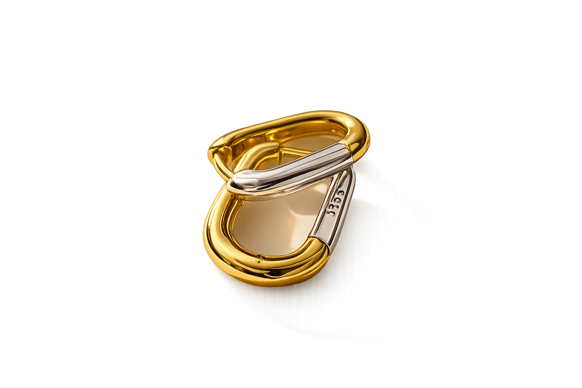 A gold and silver-tone metal carabiner clip, shown open on a clean white background.