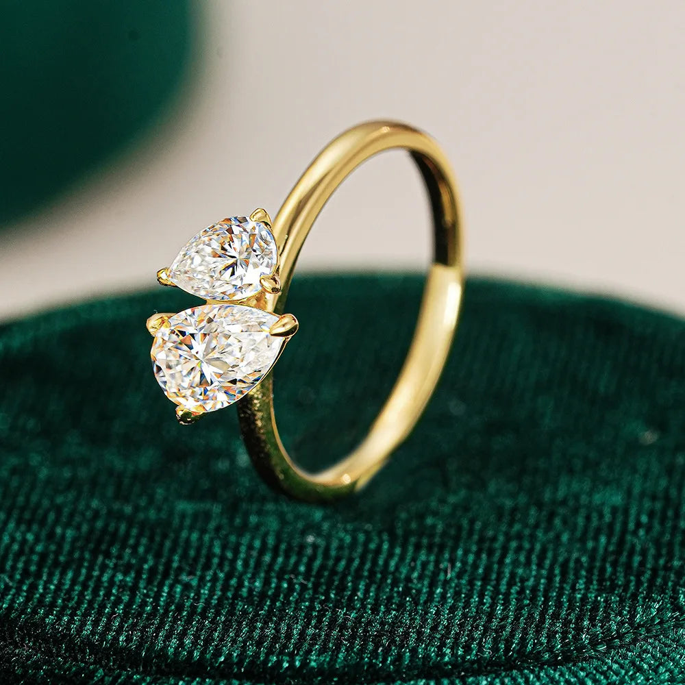 Gold ring with two pear-shaped diamonds on a green velvet surface