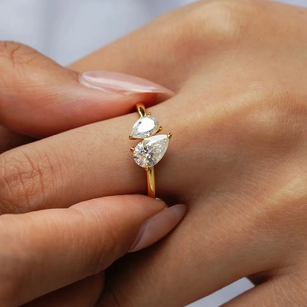 Gold ring with pear-shaped diamonds on a person's finger