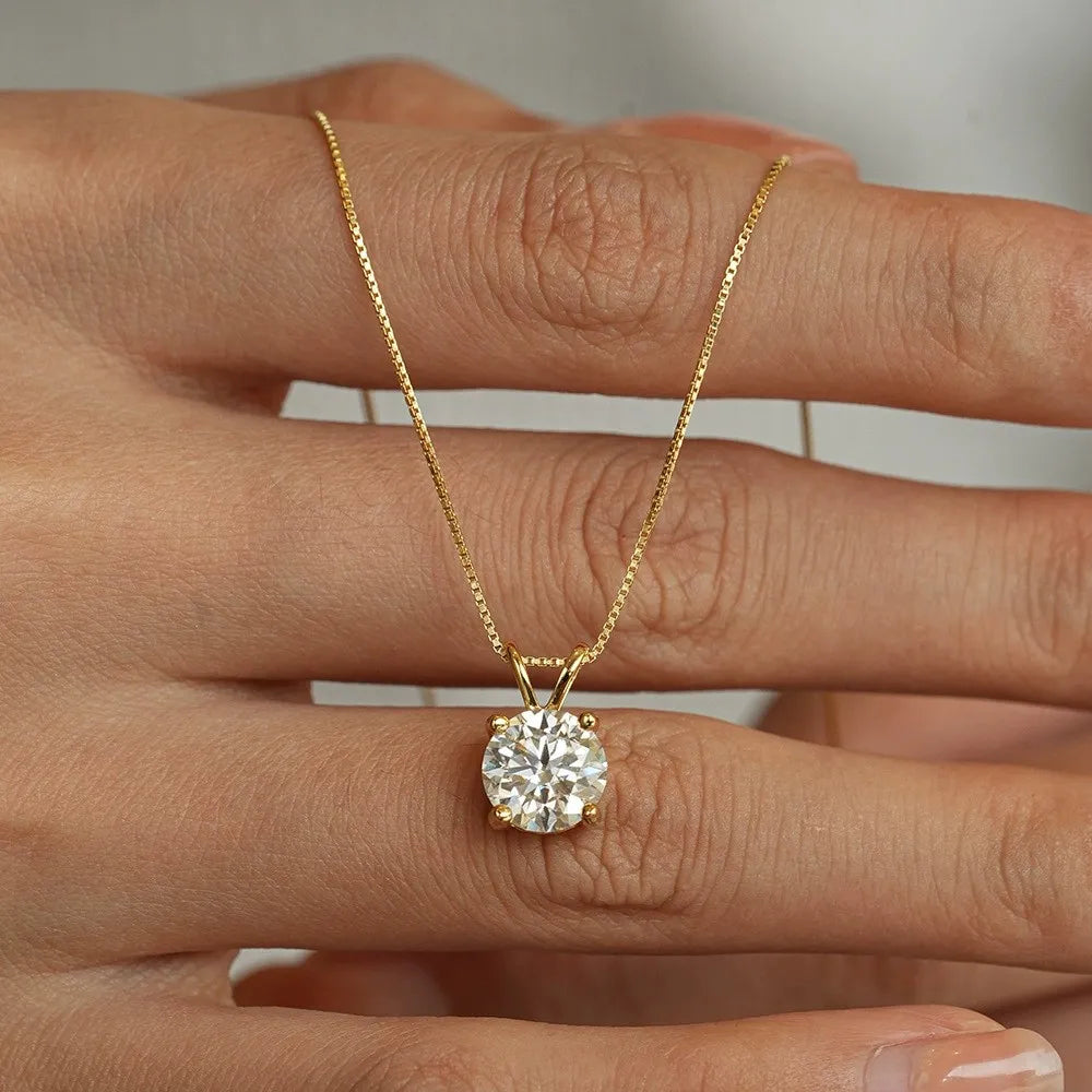 Gold necklace with a diamond pendant held between fingers