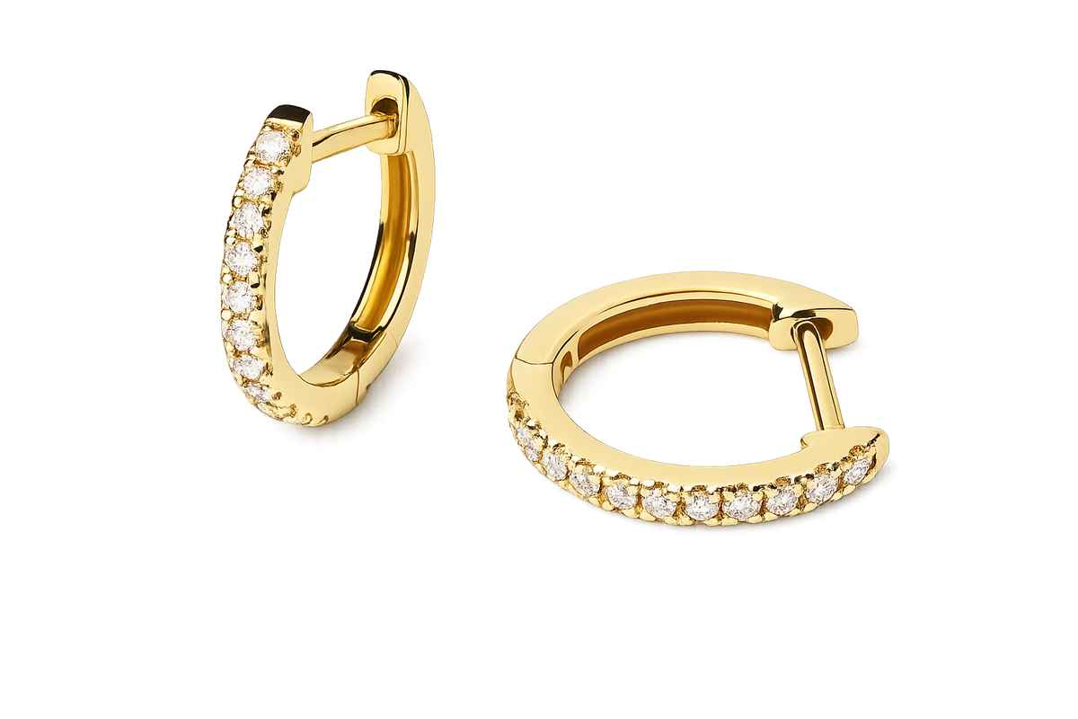 A pair of gold huggie hoop earrings with a row of clear pavé-set stones along the front curve, shown on a clean white background.