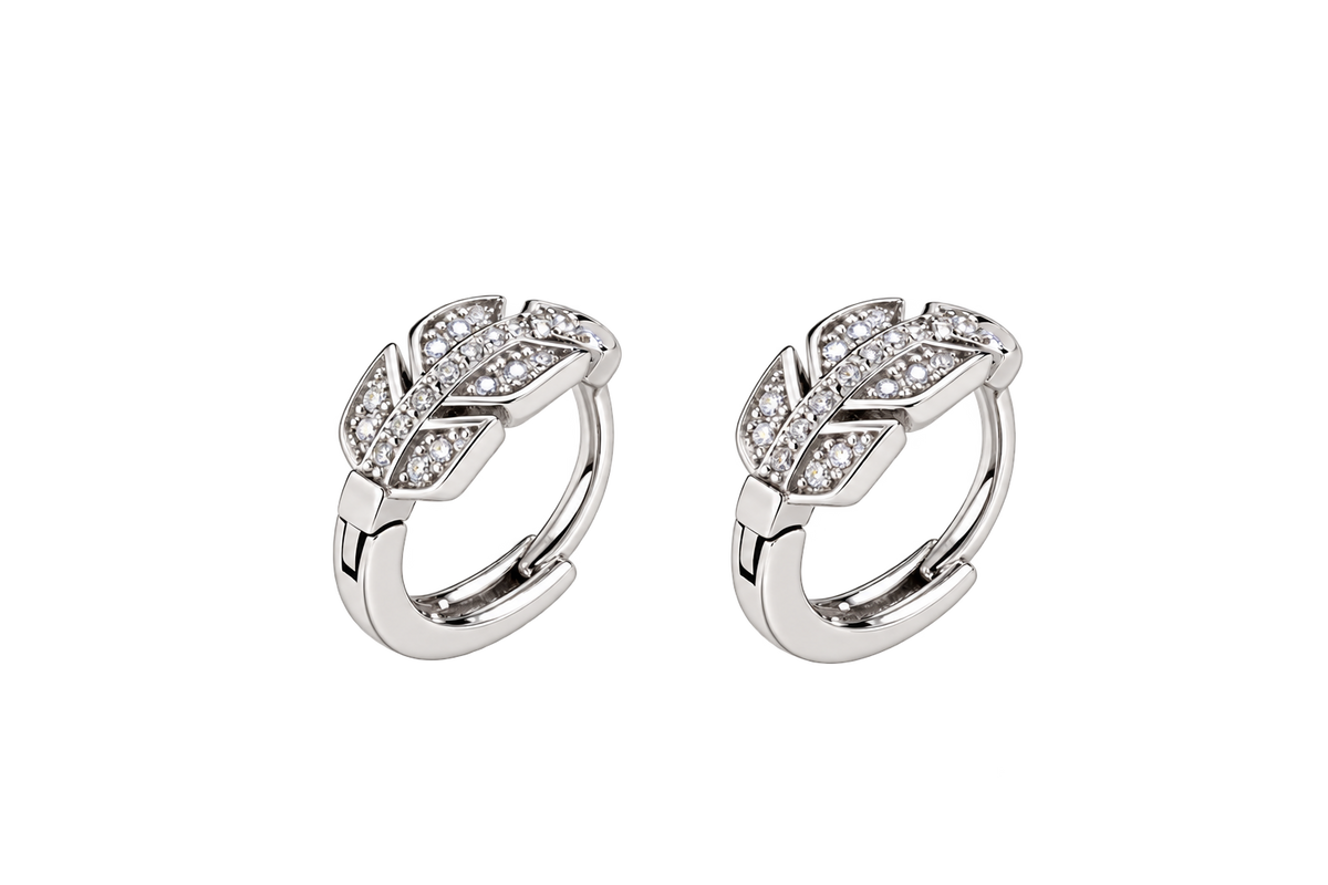 A pair of silver huggie hoop earrings with pavé-set clear crystals, arranged side by side on a solid white background.