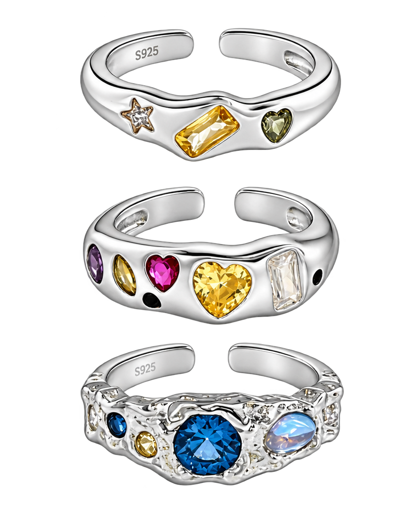 Six silver open ring bands with heart-shaped and rectangular gemstones in yellow, green, pink, blue, purple, and clear, arranged in a 2x3 grid on a white background.